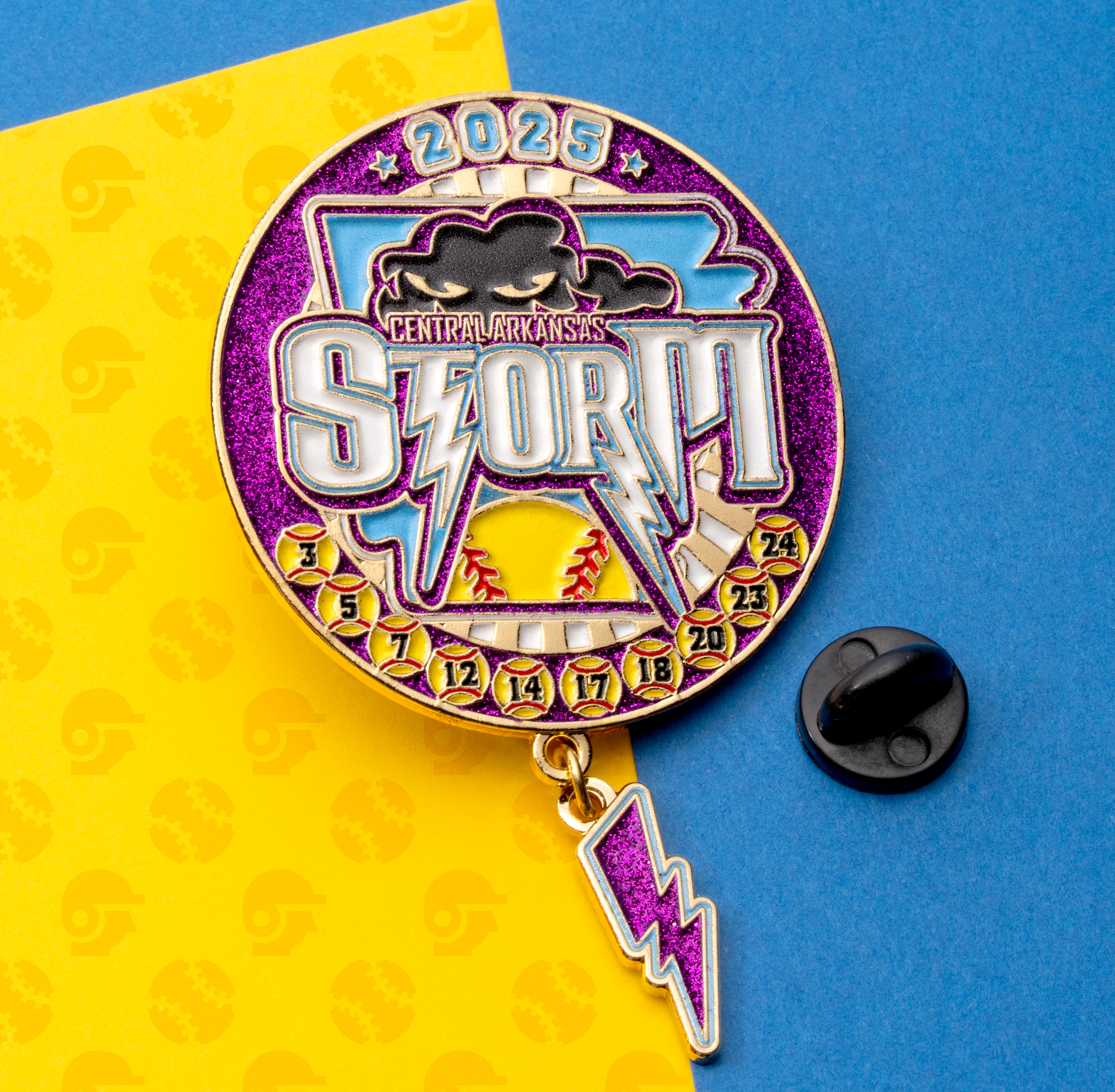 Enamel trading pin for Central Arkansas Storm 2025 featuring a softball, storm cloud, and lightning bolt dangle on a purple glitter background.